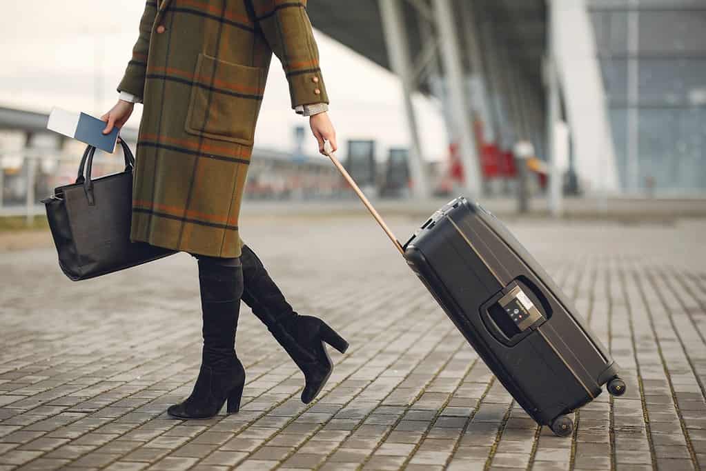Woman walking with a suitcase and a passport.