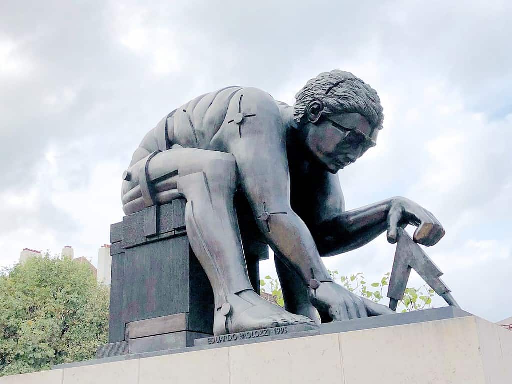 Statue of a muscular figure crouching and using a large compass, created by Eduardo Paolozzi in 1995.