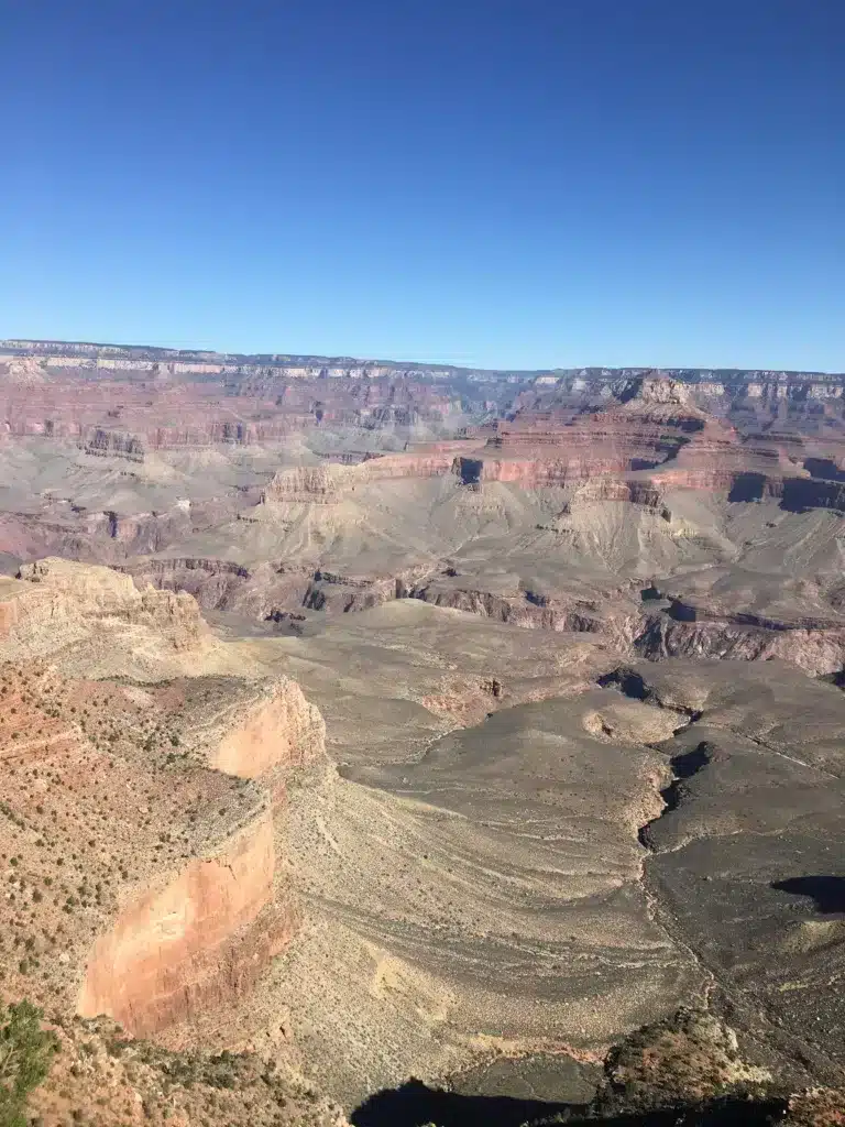 Just a short journey away from Tucson, a scenic view of the Grand Canyon unfolds under a clear blue sky, showcasing its layered rock formations and vast expanse. Perfect for day trips, this natural wonder is an awe-inspiring destination that offers unforgettable sights.