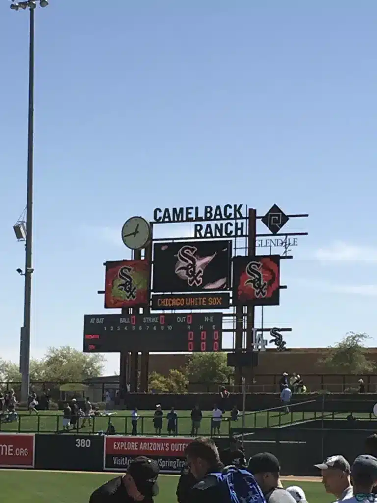 A baseball scoreboard at Camelback Ranch, perfect for day trips from Tucson, displays Chicago White Sox logos and game details against a clear blue sky.