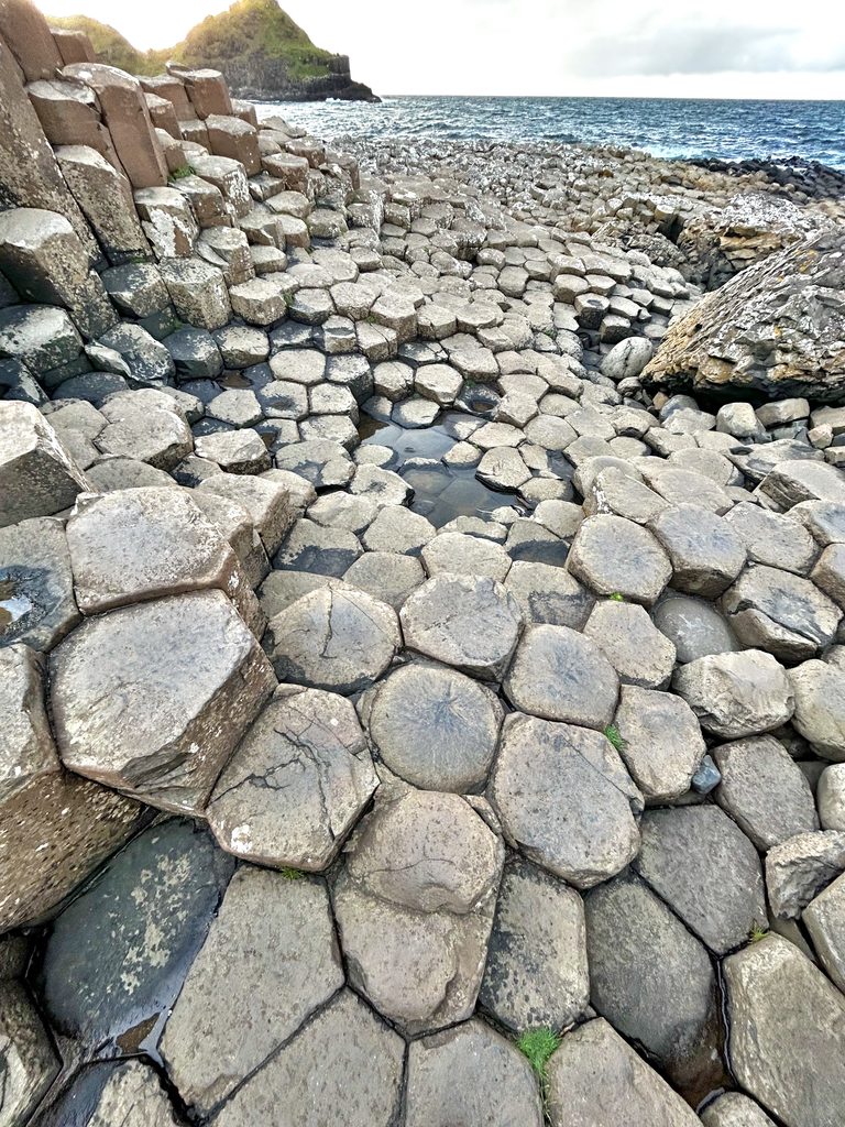 Interlocking hexagonal basalt columns at the Giant’s Causeway, a highlight among the best things to do in Belfast, leading toward the sea.