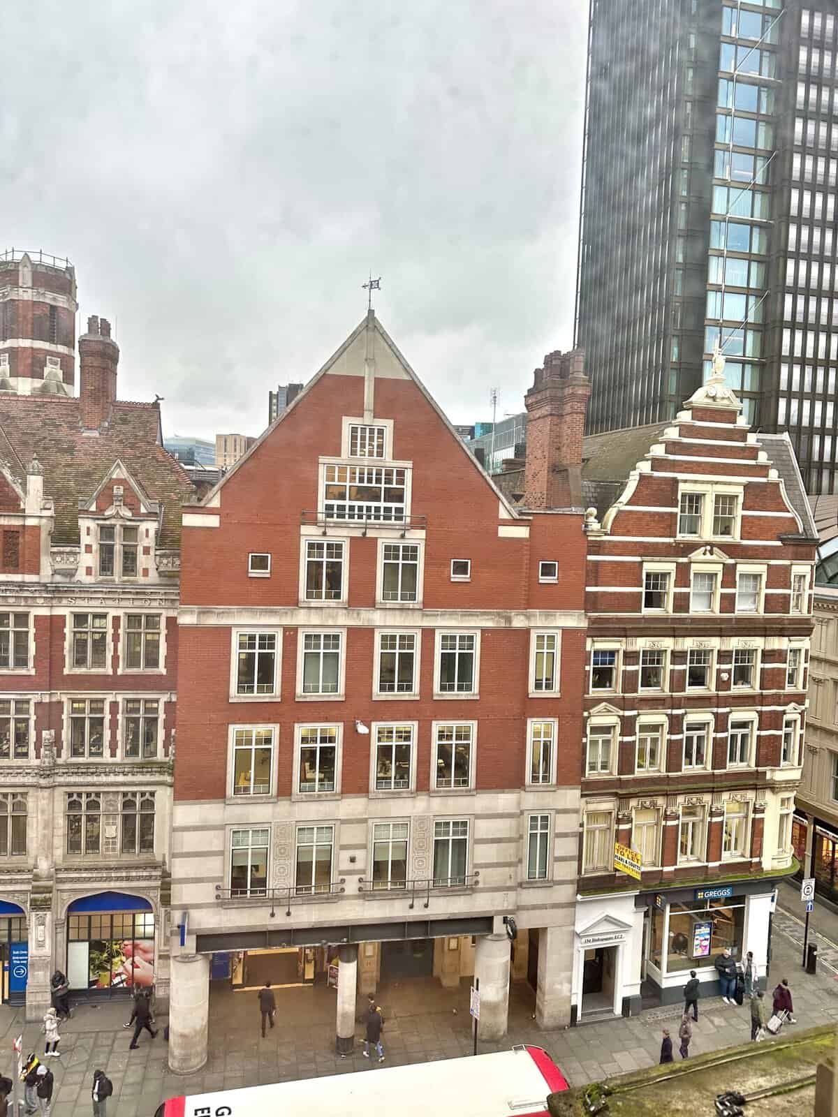 A street-level view of historic brick buildings at the Andaz London Liverpool Street, with a modern skyscraper in the background.