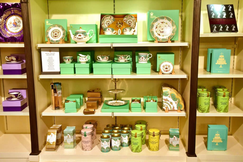 Shelves display green boxes of tea sets, mugs, tins, and books—perfect souvenirs for those exploring London things to do for free. Purple packaged items catch the eye on the left and upper right shelves.