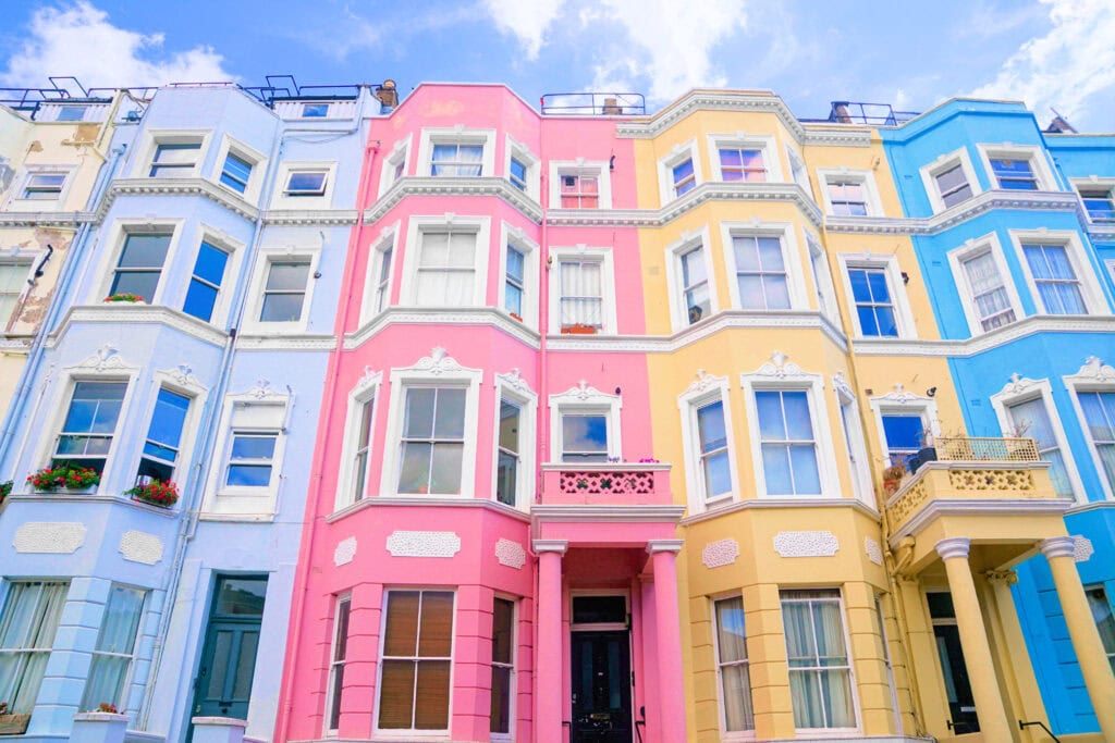Colorful Victorian-style townhouses with blue, pink, and yellow facades line the street on a sunny day—a picture-perfect scene that’s among the classic London things to do for free.
